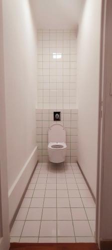 a bathroom with a toilet in a white tiled floor at Jacuzzi LOVE Suite in Paris