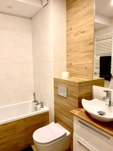a bathroom with a toilet and a sink and a tub at Apartament Nowomiejska in Suwałki