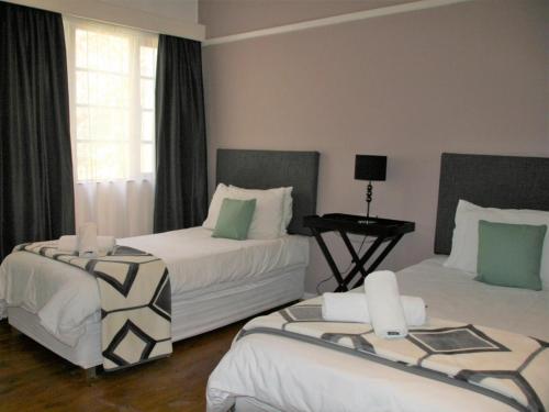Cette chambre comprend 2 lits et une table. dans l'établissement Somerset Guest Lodge - Western Cape, à Somerset West