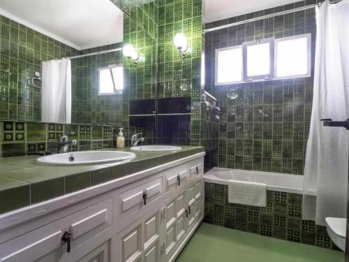 a green tiled bathroom with two sinks and a tub at Villa Azahara in Nerja
