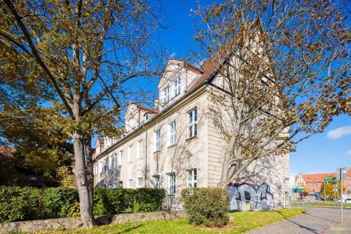 a large white building with a tree in front of it at Philharmonic Apartment in Szczecin