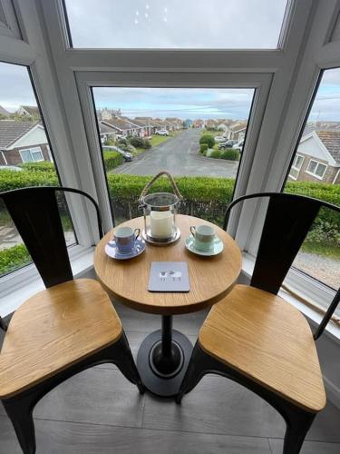 a table and two chairs in a room with a window at Tywyn seaside apartment with Mountain View in Tywyn