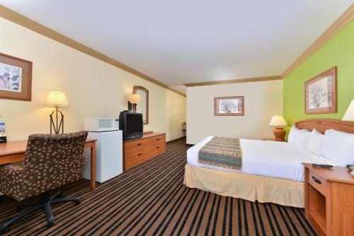 a hotel room with a bed and a desk and a computer at Americas Best Value Inn Vacaville in Vacaville