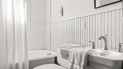 bagno bianco con vasca, lavandino e servizi igienici di Callicoon Hills a Callicoon Center