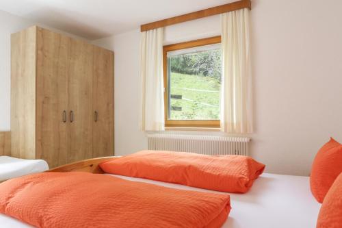 a bedroom with two beds with orange sheets and a window at Ferienwohnungen Ötztal in Sautens