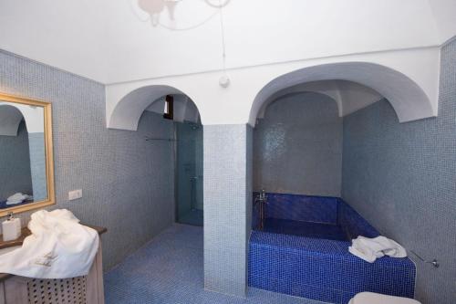 bagno con vasca blu e lavandino di Resort Acropoli a Pantelleria