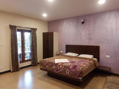 a bedroom with a large bed with a purple wall at The Atmosphere Resort Kotagiri By LexStays in Kotagiri