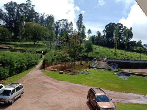 two cars parked on a dirt road next to a field at The Atmosphere Resort Kotagiri By LexStays in Kotagiri