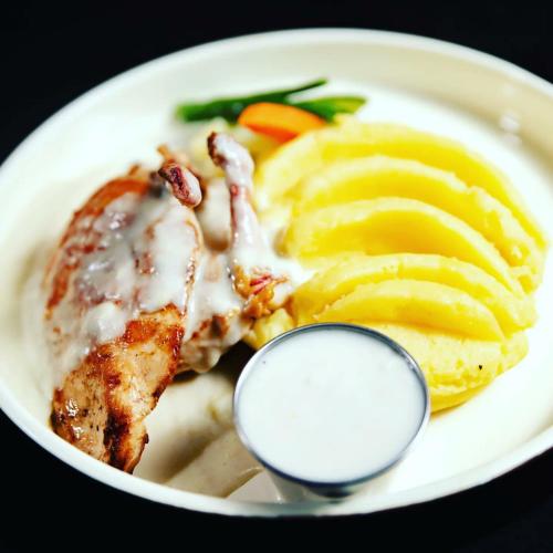 a plate of food with meat and fruit and a spoon at Romeos Hotel in Kampala