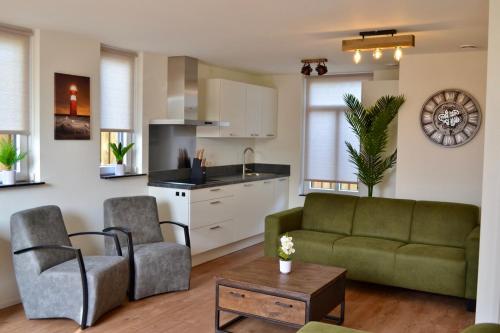 a living room with a green couch and a kitchen at Luxe vakantievilla Zoutelande in Zoutelande