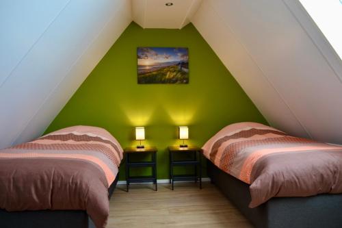 two beds in a room with a green wall at Luxe vakantievilla Zoutelande in Zoutelande