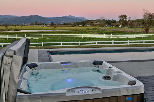 a hot tub on a patio with a view of a field at Sanctuary On Lytton A Wine Country Escape in Geyserville