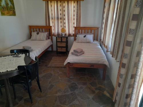 two beds in a room with a table and a table and chairs at Ombo Rest Camp in Okahandja