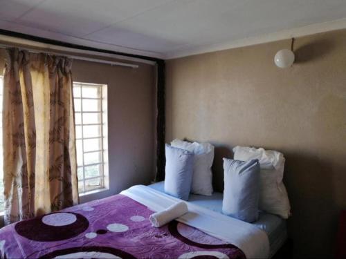 a bedroom with a bed with pillows and a window at Kaste guesthouse Tzaneen in Tzaneen