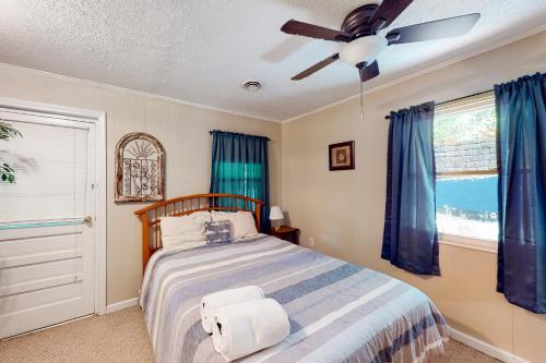 een slaapkamer met een bed met blauwe gordijnen en een plafondventilator bij A Quiet Cove in Moneta