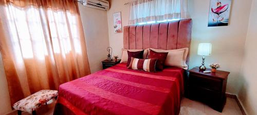 a bedroom with a red bed with a red blanket at Acogedor Espacio en Santo Domingo Este. in Mandinga