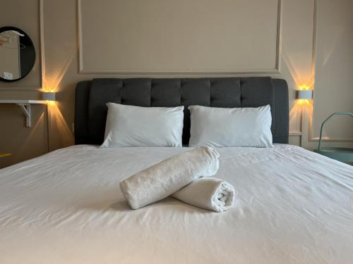 a white towel laying on a bed with two pillows at Splendours Condos@Jesselton Quay in Kota Kinabalu