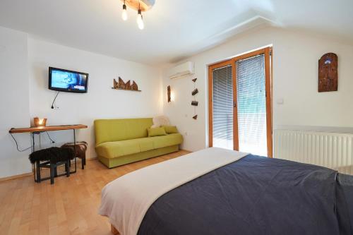 a bedroom with a bed and a couch and a television at Guesthouse S in Luče