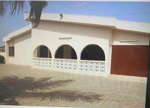 a white house with arched windows and a garage at Exclusive Holiday Villa with Pool in Accra in Accra