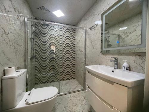 a bathroom with a shower and a toilet and a sink at Luxe Azure Apartment in Baku