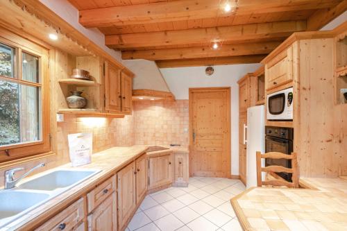 cocina con armarios de madera, fregadero y microondas en Chalet Persévérance, en Chamonix-Mont-Blanc