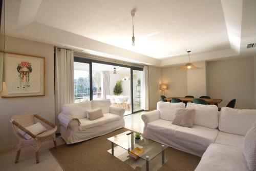 una sala de estar con sofás blancos y una mesa. en Sotogrande Alboaire- Waterfront luxury 4 bedroom Apt in the Marina of Sotogrande, en Sotogrande