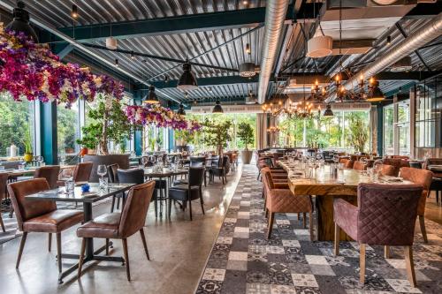 a restaurant with tables and chairs and plants at Holiday Inn Hotel Brussels Airport by IHG in Diegem