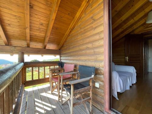 a log cabin with a bed and chairs on a porch at Chalet Klimatia - Όμορφη ξύλινη μεζονέτα με τζάκι in Klimatiá