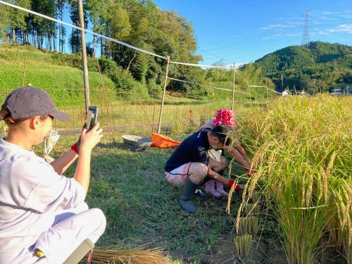 a man taking a picture of two girls in a field at 一汁一菜の宿 ちゃぶダイニング Ichiju Issai no Yado Chabu Dining, A Private Farmstay in Rural Kyoto in Ayabe