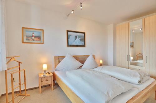 1 dormitorio con 1 cama con sábanas blancas y 2 lámparas en Haus Strandallee 24 Haus Strandallee 24 - Appartement Seemanns Meeresblick, en Scharbeutz