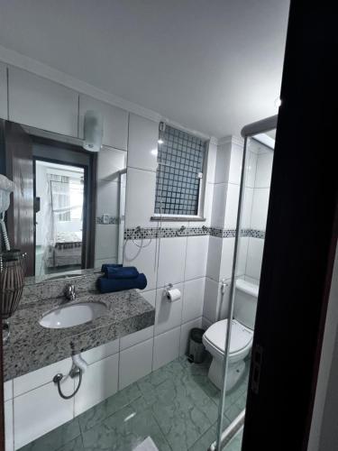 a bathroom with a sink and a toilet and a mirror at Flat Bela Vista in Macaé