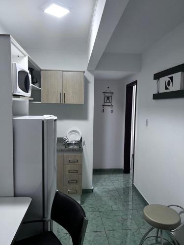 a kitchen with a refrigerator and a table and a chair at Flat Bela Vista in Macaé