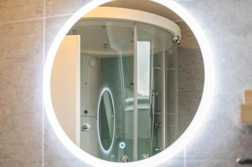 a round mirror in a bathroom with a shower at Alpen Living - 2 Stock in Cadipietra