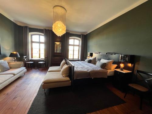 a bedroom with a bed and a couch and a chandelier at Gutshaus Klein kussewitz in Klein Kussewitz