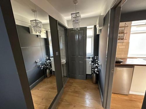 a hallway with a door and a kitchen with flowers at BRAND NEW LARGE Studio Flat! in Hackbridge