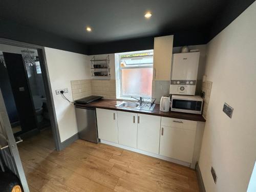 a small kitchen with a sink and a microwave at BRAND NEW LARGE Studio Flat! in Hackbridge