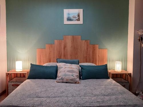 - une chambre avec un lit avec une tête de lit en bois et deux lampes dans l'établissement Cocoon'House, à Gruissan
