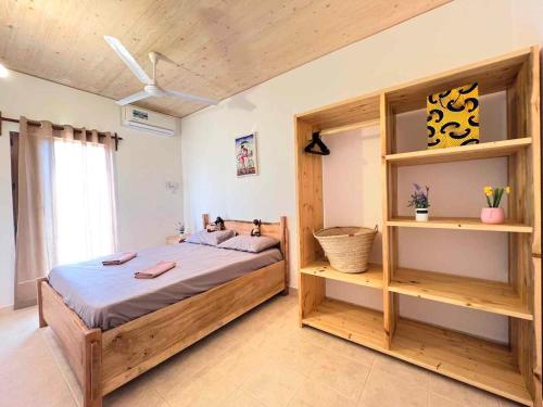 a bedroom with a large wooden bed and shelves at Homerent @ Fumba-Town in Dambani