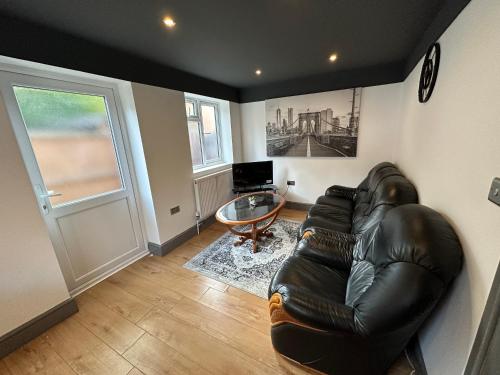 a living room with a leather couch and a glass table at BRAND NEW LARGE Studio Flat! in Hackbridge