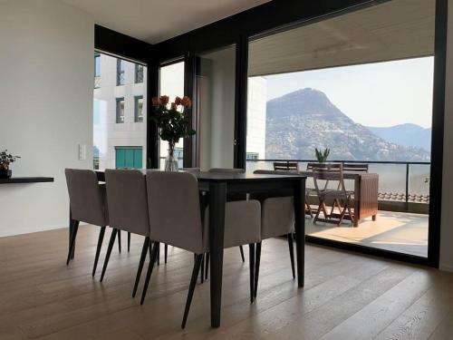 a dining room table with chairs and a view of the ocean at Live Lugano - Via Massagno in Lugano