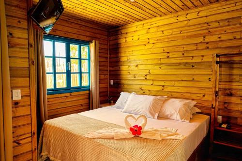 ein Schlafzimmer mit einem Bett mit einer roten Schleife darauf in der Unterkunft Prana Guest House in Praia do Rosa