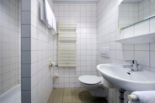 a white bathroom with a sink and a toilet at Olympia Hotel Suhl in Suhl