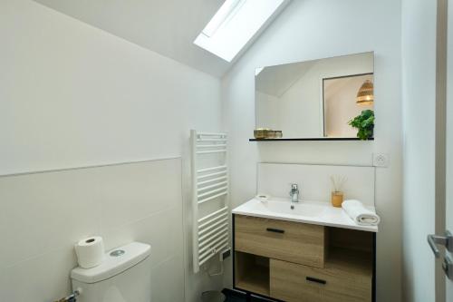 une salle de bain blanche avec un lavabo et un miroir dans l'établissement Le perchoir *hyper centre * A 2 pas de la mer *, à Concarneau