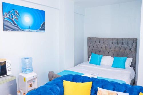 a bedroom with a bed and a blue couch at LaMeg Furnished Studio in Fedha in Nairobi
