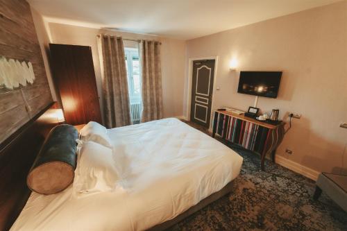 a bedroom with a large bed and a television at Logis Hôtels Château de La Barge in Chaintré