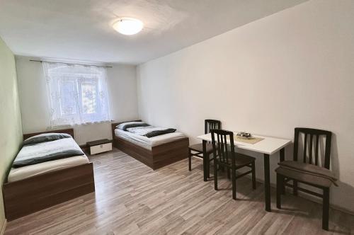 Cette chambre comprend deux lits, une table et des chaises. dans l'établissement Penzion Zahrádka, à Lázně Bohdaneč