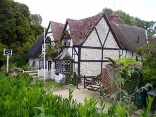 a white and black house with a bench in a garden at White Horse Inn in Woolstone