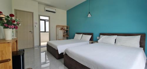a bedroom with two beds and a blue wall at BREAKING DAWN- TAEYANG Hotel Phú Quốc in Phu Quoc