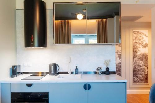 a kitchen with blue cabinets and a sink and a mirror at Warsaw Story - LoftAffair Collection in Warsaw