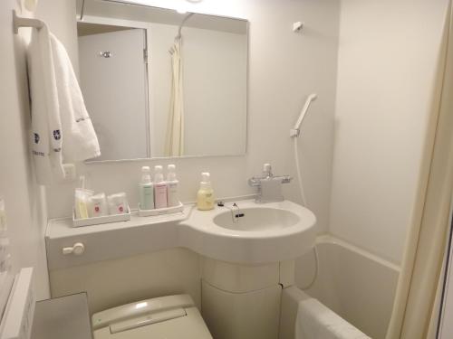a bathroom with a sink and a toilet and a mirror at Hotel Sunroute Aomori in Aomori
